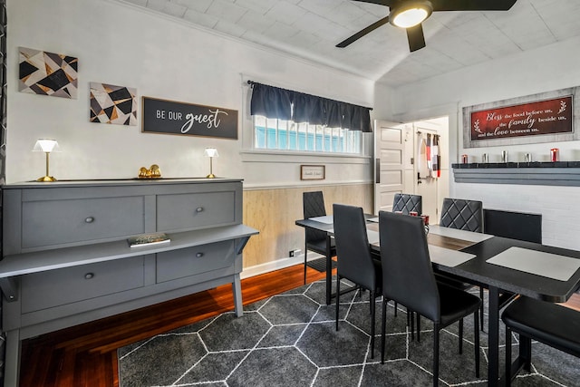 dining space with ornamental molding, ceiling fan, dark wood-type flooring, and wood walls