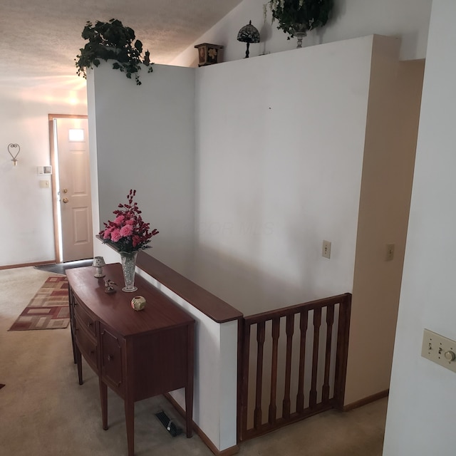 hallway featuring lofted ceiling and light colored carpet