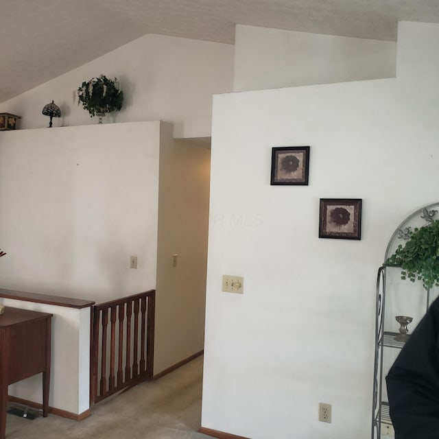 hall featuring vaulted ceiling and light carpet