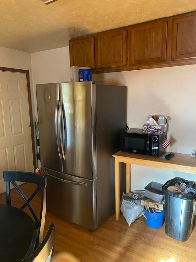 kitchen with stainless steel fridge and light hardwood / wood-style flooring