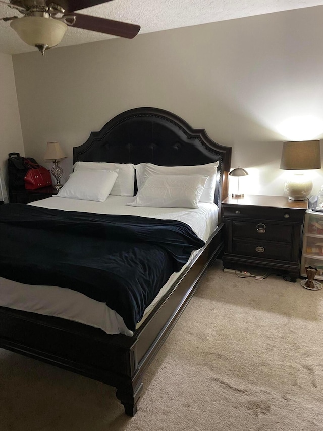 bedroom featuring ceiling fan, light colored carpet, and a textured ceiling