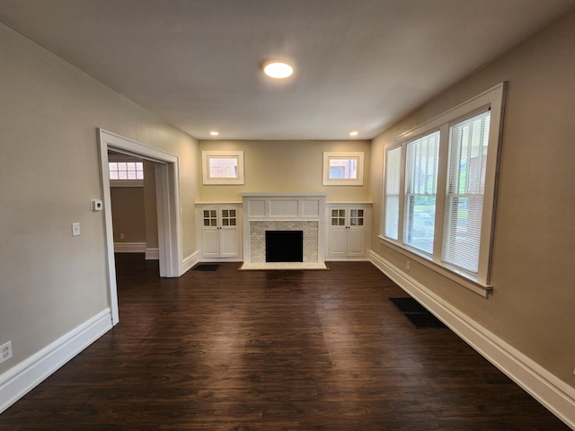 unfurnished living room featuring a fireplace, dark hardwood / wood-style floors, and a wealth of natural light