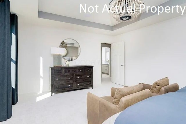 carpeted bedroom featuring a raised ceiling and a chandelier