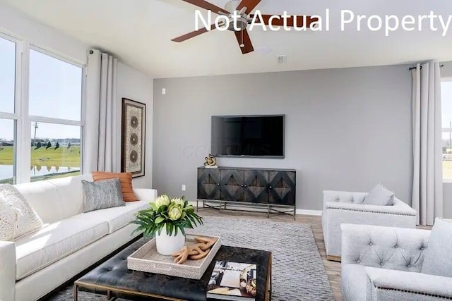 living room with ceiling fan, visible vents, baseboards, and wood finished floors