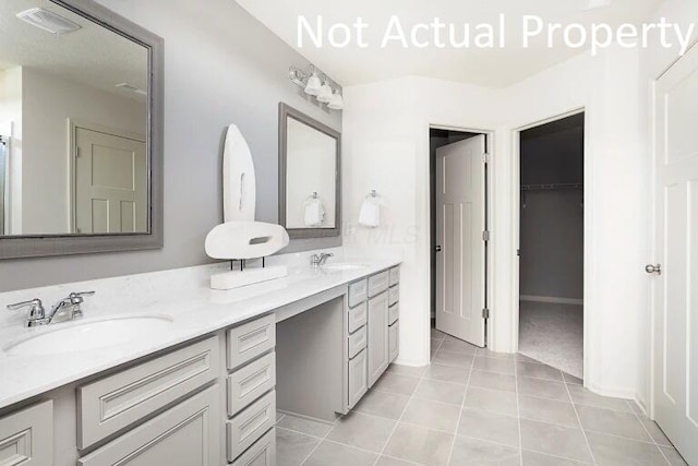 full bath with a sink, visible vents, double vanity, and tile patterned floors