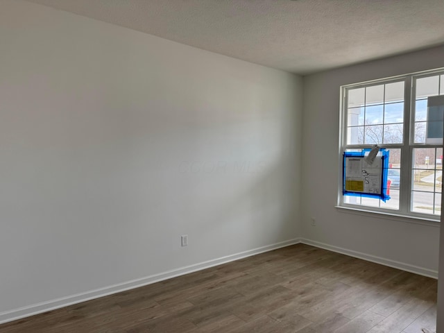 unfurnished room with a healthy amount of sunlight, dark hardwood / wood-style floors, and a textured ceiling