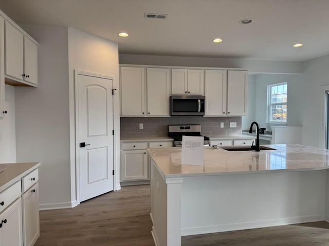 kitchen with white cabinetry, appliances with stainless steel finishes, sink, and a center island with sink