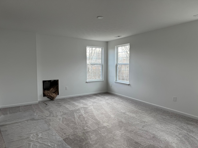 unfurnished living room featuring light colored carpet and a fireplace