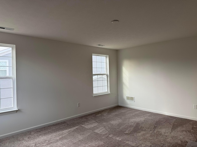 carpeted empty room with a textured ceiling