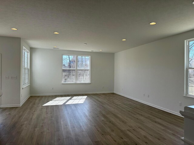 empty room featuring recessed lighting, baseboards, and dark wood-style flooring