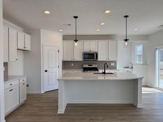 kitchen with visible vents, a sink, stainless steel appliances, white cabinetry, and backsplash