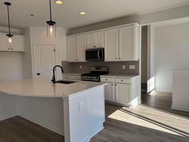 kitchen featuring backsplash, appliances with stainless steel finishes, white cabinetry, and a sink