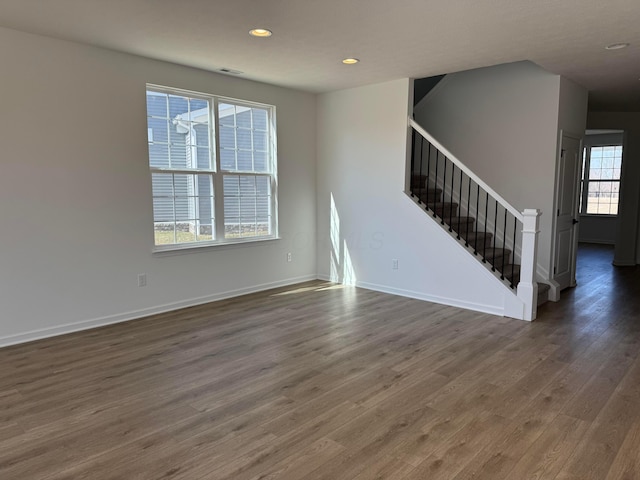 empty room featuring visible vents, baseboards, stairway, recessed lighting, and wood finished floors