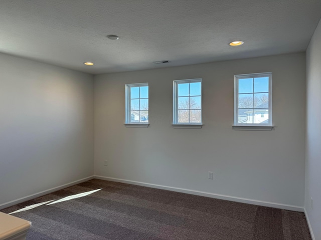 unfurnished room with baseboards, dark colored carpet, and a wealth of natural light