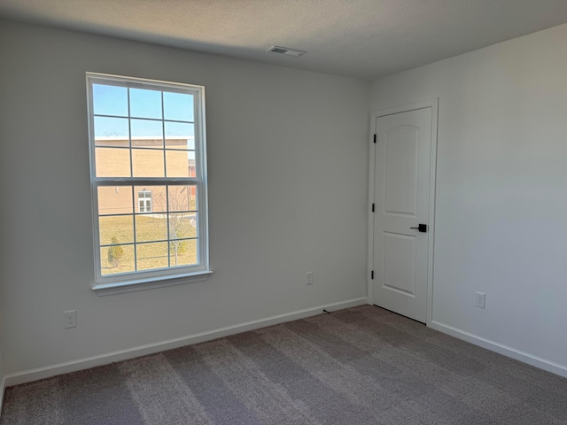 carpeted empty room featuring visible vents, a textured ceiling, and baseboards