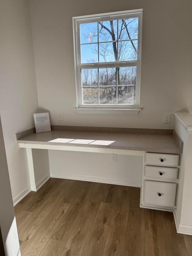 unfurnished office with a healthy amount of sunlight, built in study area, and dark wood-type flooring