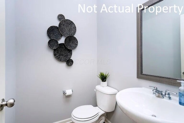 bathroom with toilet, baseboards, and a sink