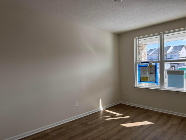 unfurnished room with baseboards, a textured ceiling, and dark wood finished floors