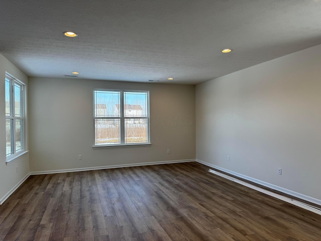 spare room with dark wood finished floors, recessed lighting, a textured ceiling, and baseboards