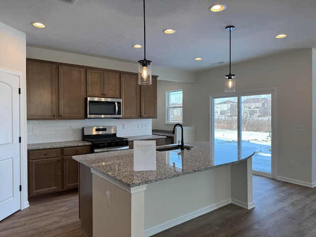 kitchen with tasteful backsplash, appliances with stainless steel finishes, dark wood-type flooring, and a sink