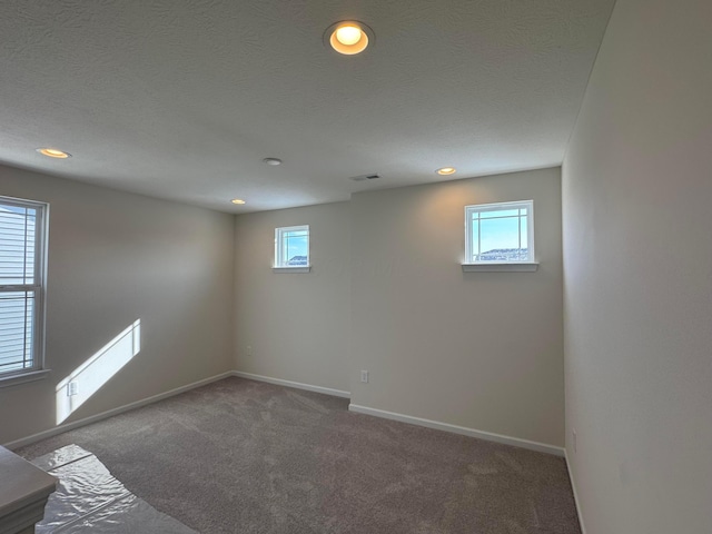 below grade area with carpet, visible vents, baseboards, recessed lighting, and a textured ceiling