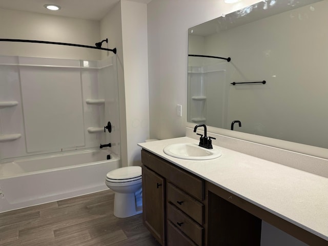 bathroom with vanity, toilet, wood finished floors, and shower / washtub combination