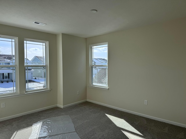 unfurnished room with visible vents, baseboards, a textured ceiling, and carpet floors