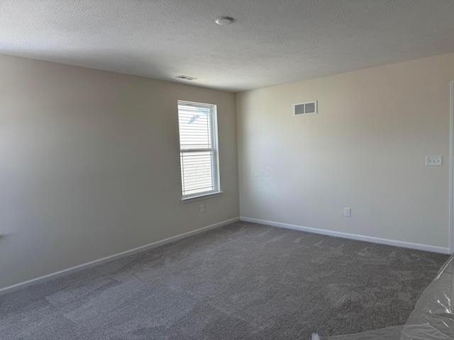 unfurnished room with baseboards, visible vents, dark colored carpet, and a textured ceiling