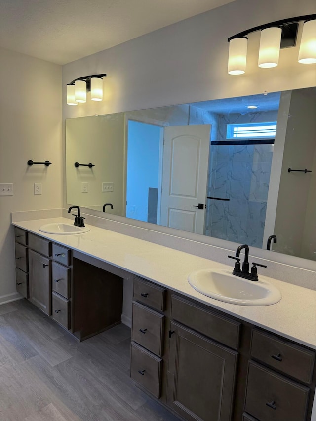 bathroom with double vanity, walk in shower, wood finished floors, and a sink