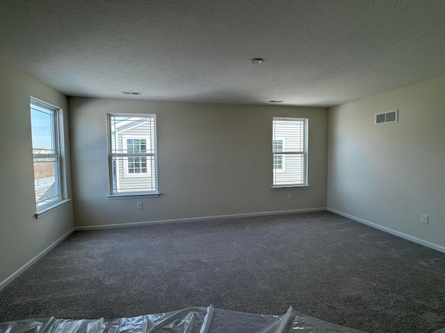 carpeted empty room featuring visible vents, a textured ceiling, and baseboards