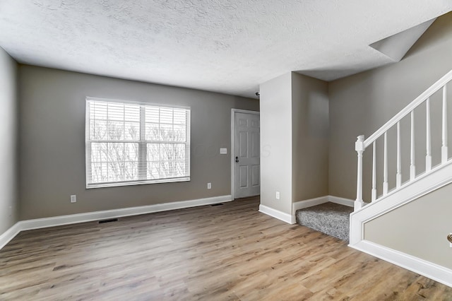 spare room with a textured ceiling and light hardwood / wood-style flooring