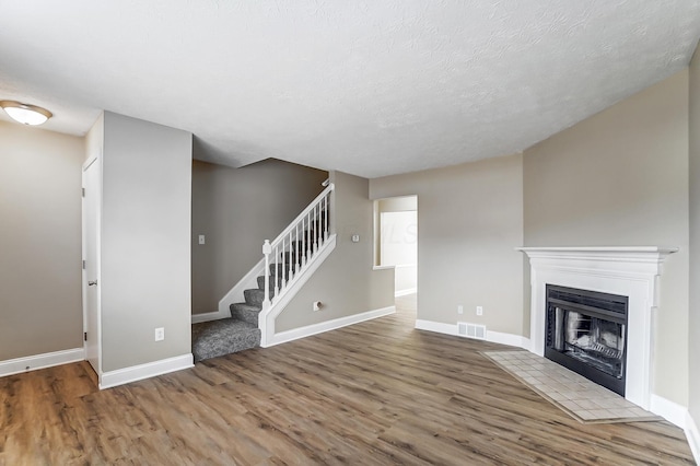 unfurnished living room with hardwood / wood-style flooring and a textured ceiling