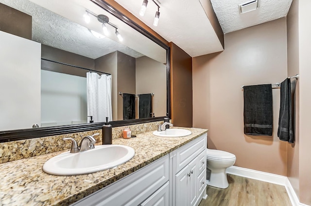 bathroom with wood-type flooring, toilet, a textured ceiling, and vanity