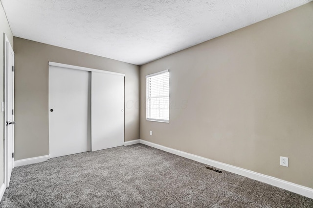 unfurnished bedroom with a closet, carpet, and a textured ceiling