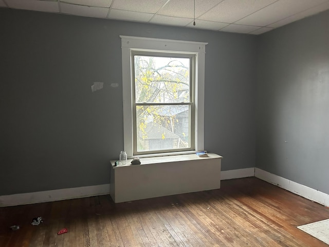 spare room featuring a drop ceiling and wood-type flooring