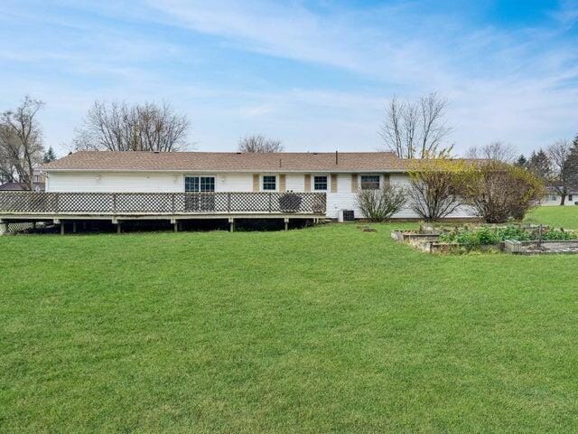 back of property with a deck and a yard