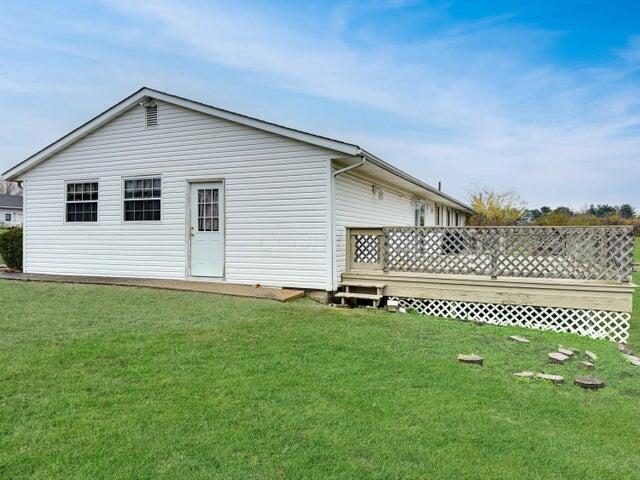 back of property with a deck and a lawn