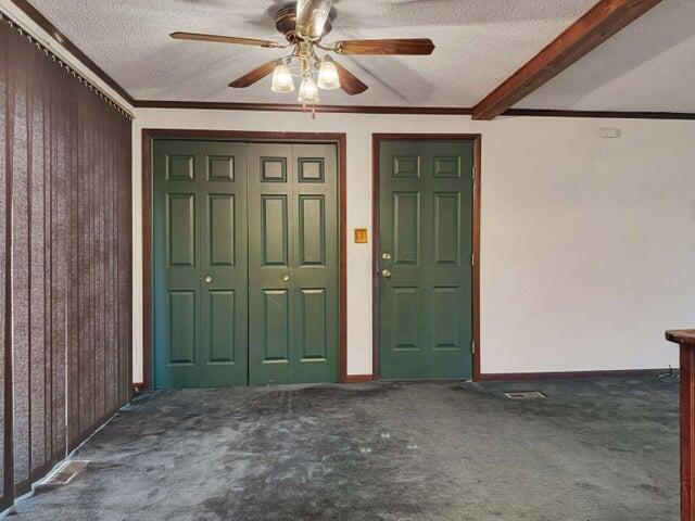 interior space featuring ceiling fan, a textured ceiling, ornamental molding, and beamed ceiling