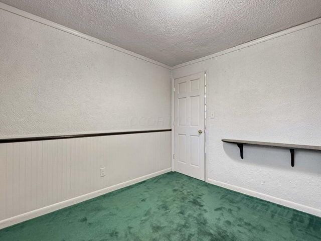 carpeted empty room with a textured ceiling and ornamental molding