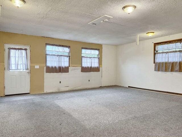 unfurnished room with a textured ceiling, carpet flooring, and a baseboard radiator