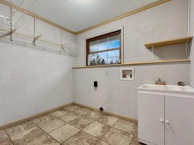 laundry room with a textured ceiling, cabinets, sink, ornamental molding, and hookup for a washing machine