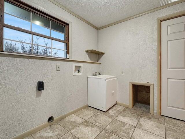 washroom featuring washer hookup, sink, a textured ceiling, and crown molding