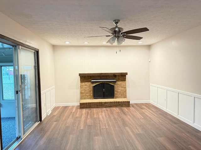 unfurnished living room featuring a fireplace, hardwood / wood-style floors, a textured ceiling, and ceiling fan