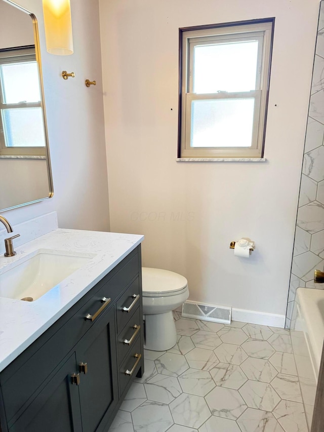 bathroom featuring vanity, a bathtub, and toilet