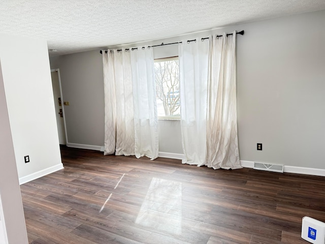 spare room with a textured ceiling and dark wood-type flooring