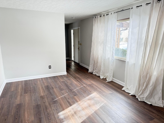 spare room with a textured ceiling and dark wood-type flooring