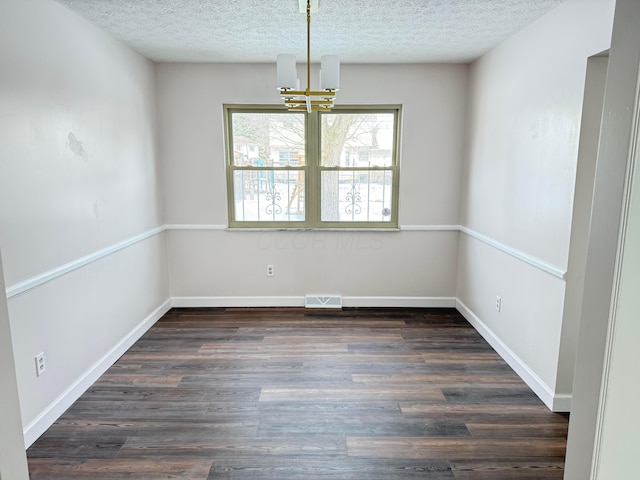 unfurnished dining area featuring dark wood-type flooring, a chandelier, and a textured ceiling