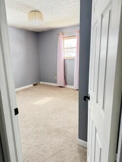 hall with a textured ceiling and light colored carpet