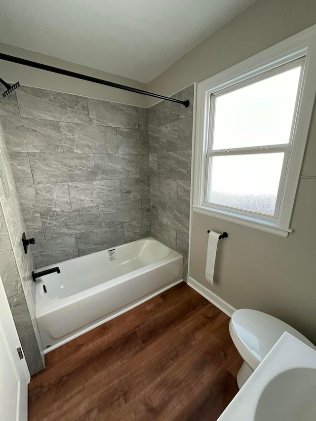 bathroom featuring toilet, tiled shower / bath combo, and hardwood / wood-style flooring