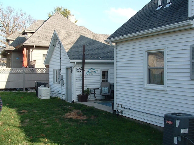 view of side of property featuring central AC unit and a lawn